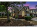 Beautiful dusk view of a tan townhouse with green grass and manicured landscaping at 247 Darcy Ave, Goose Creek, SC 29445