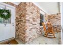 Cozy front porch with brick accents, rocking chairs, and a wreath on the front door at 7 Sconesill Ln, Charleston, SC 29414