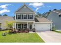 Well-maintained two-story home with a covered porch, landscaped front yard, and attached two-car garage at 127 Surfbird Rd, Summerville, SC 29486