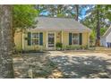 Charming one-story home featuring yellow siding, blue shutters, and a well-manicured lawn with mature trees at 1507 Blaze Ln, Charleston, SC 29412