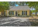 Charming one-story home featuring yellow siding, blue shutters, and a well-manicured lawn with mature trees at 1507 Blaze Ln, Charleston, SC 29412