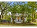 Beautiful white home with a inviting front porch framed by mature trees and lush landscaping at 2 Pagett St, Daniel Island, SC 29492