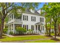 Stately two-story home with a double porch, manicured lawn, and mature trees offering shade at 2 Pagett St, Daniel Island, SC 29492