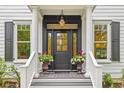 Elegant front entrance with black door, white columns, decorative lighting, and potted flowers at 2 Pagett St, Daniel Island, SC 29492