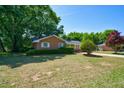 Inviting single-story brick home with a well-manicured lawn and mature trees on a sunny day at 779 Dills Bluff Rd, Charleston, SC 29412