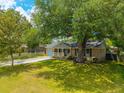 Single-story home with a welcoming front porch, well-kept lawn, and mature shade trees at 104 Greensboro Ln, Ladson, SC 29456