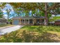 Single story home with a welcoming front porch, well-kept lawn, and mature trees at 104 Greensboro Ln, Ladson, SC 29456