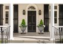 Front porch with black door, black shutters, and decorative potted plants at 12 Orange St, Charleston, SC 29401