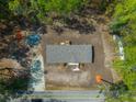 Birds eye view of single-story house with gray roof surrounded by dense trees and green grass and small yard at 120 Perry Hill Rd, Moncks Corner, SC 29461