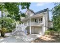 Angle view of the stilted home with a double porch, staircase, and a two-car garage at 1325 Moss Path, Mount Pleasant, SC 29464