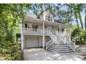 Side angle of the home with a porch, staircase, and a garage under the elevated structure at 1325 Moss Path, Mount Pleasant, SC 29464