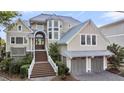 Beautiful multi-story home with manicured landscaping, grand entrance staircase, and attached garage at 3128 Palmetto Blvd, Edisto Island, SC 29438