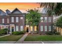 Brick townhome featuring a well-manicured lawn and inviting front entrance at sunset at 822 Rue Dr, Charleston, SC 29414