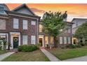 Brick townhome featuring a well-manicured lawn and inviting front entrance at dusk at 822 Rue Dr, Charleston, SC 29414