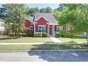 Red house with a manicured lawn, mature landscaping and inviting covered porch at 1126 Rearick Rd, Johns Island, SC 29455