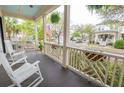 Inviting front porch with rocking chairs and hanging ferns overlooking a peaceful street at 1445 Lettered Olive Ln, Mount Pleasant, SC 29464