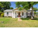 Charming home features a manicured lawn and covered porch with an inviting orange front door at 1474 Indian St, Mount Pleasant, SC 29464