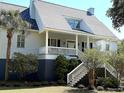 Inviting home featuring a spacious front porch, well-maintained landscaping, and classic architectural details at 2624 Jenkins Point Rd, Seabrook Island, SC 29455