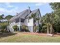 Charming coastal home with a welcoming front porch, lush landscaping, and mature palm trees at 2624 Jenkins Point Rd, Seabrook Island, SC 29455