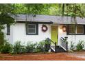 Close-up of the house with black and white trim and a vibrant green door with matching wreaths at 3293 River Rd, Johns Island, SC 29455