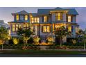 Elegant home featuring landscaped grounds, a welcoming entryway, and beautifully illuminated windows in the evening at 332 Bayley Rd, Daniel Island, SC 29492