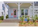 Inviting front porch with seating area, a pink door, and beautiful landscaping at 503 Ivy Green Ln, Summerville, SC 29486
