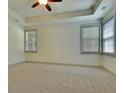 A serene bedroom boasts neutral carpeting and tray ceilings, complemented by natural light from the windows at 8633 Connor Ct, North Charleston, SC 29406