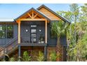 Close-up of home exterior with wooden accents and a small front porch lined with tropical foliage at 1014 E Erie Ave, Folly Beach, SC 29439