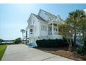 Elegant white home features a two-car garage, a charming balcony and bay window, plus lush landscaping with a view of the river at 1531 Murphys Island Ct, Awendaw, SC 29429