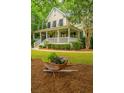 Landscaped front yard featuring lush greenery and a decorative wheelbarrow planter at 225 River Oak Dr, Mount Pleasant, SC 29464