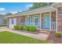 Close-up of a charming porch and entrance with blue door, brick facade, and neatly trimmed green bushes at 2534 Flamingo Dr, Charleston, SC 29414