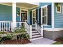 Inviting front porch with white railings and stairs, complemented by a black front door and exterior lights at 2627 Rutherford Way, Charleston, SC 29414