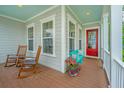 Relaxing front porch with rocking chairs, vibrant flower pot, and a charming red door entrance at 2962 Clearwater Dr, Mount Pleasant, SC 29466