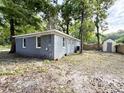Spacious backyard featuring a gray brick home, ample green space, a storage shed, and mature trees at 354 Deloach Ave, Walterboro, SC 29488