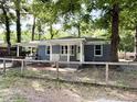 Quaint exterior view showcasing the charming blue brick home with a fenced yard, mature trees, and inviting front porch at 354 Deloach Ave, Walterboro, SC 29488