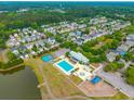 An aerial view of a community with a large pool, playground, a pond, and surrounded by lush green trees at 422 Verbena Ave, Summerville, SC 29483