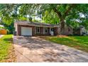 A charming brick home featuring a one-car garage and a wide driveway, shaded by mature trees at 4327 Bream Rd, North Charleston, SC 29418