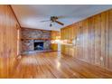 Spacious living room with hardwood floors, brick fireplace, and wood-paneled walls, adjacent to the kitchen at 4327 Bream Rd, North Charleston, SC 29418
