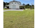 Charming white barn-style home with a covered carport and well-maintained lawn showcasing its unique architecture at 795 Shagule Rd, Edisto Island, SC 29438