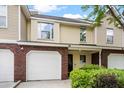 Two-story tan townhome featuring a brick front, a single-car garage, and manicured bushes at 8676 Grassy Oak Trl, North Charleston, SC 29420