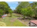 Expansive backyard with mature trees, a fire pit, garden beds, and storage sheds at 9666 Jamison Rd, Ladson, SC 29456