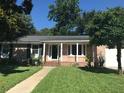Charming brick home with a green lawn, trimmed hedges and a covered front porch at 1010 Foxcroft Rd, Charleston, SC 29412