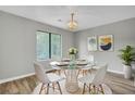 Modern dining area featuring a glass-top table, white chairs, a chandelier, and a large window at 108 Greenmeadow Dr, Goose Creek, SC 29445