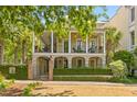 Elegant two-story home featuring a spacious double porch with white pillars, surrounded by lush greenery at 121 W Shipyard Rd, Mount Pleasant, SC 29464