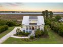 Stunning aerial view of a two-story home with a metal roof, lush yard, and waterfront property at 1500 Bower Ln, Johns Island, SC 29455