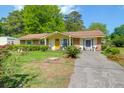 Quaint home with a bright yellow door and rocking chairs on the porch surrounded by a well kept yard at 1575 Langston Dr, Johns Island, SC 29455