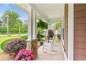Spacious front porch with stone-detailed pillars, hanging ferns, and comfortable rocking chairs at 2017 Woodland Shores Rd, Charleston, SC 29412