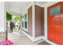 Inviting front porch featuring cozy rocking chairs, decorative plants, and a bright red door at 2017 Woodland Shores Rd, Charleston, SC 29412
