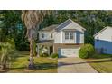 Charming home with a stone-accented base, a well-manicured lawn, and a paved driveway leading to a two-car garage at 240 Woodbrook Way, Moncks Corner, SC 29461