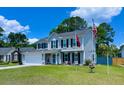 Well-kept two story home with mature landscaping, American flag, and desirable curb appeal on a sunny day at 302 Axeminster Ct, Goose Creek, SC 29445